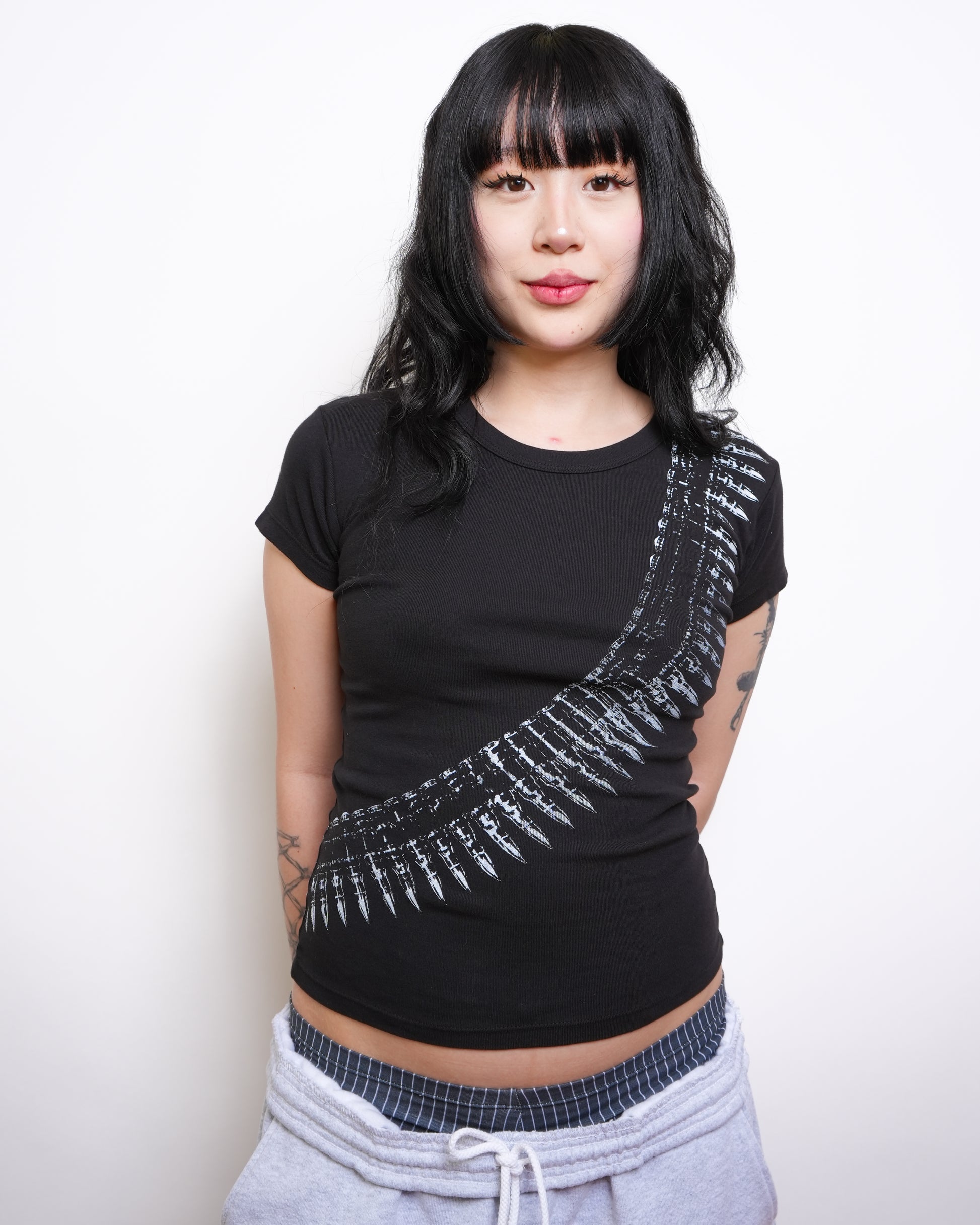 Woman wearing a black t-shirt with white graphic design on a plain background